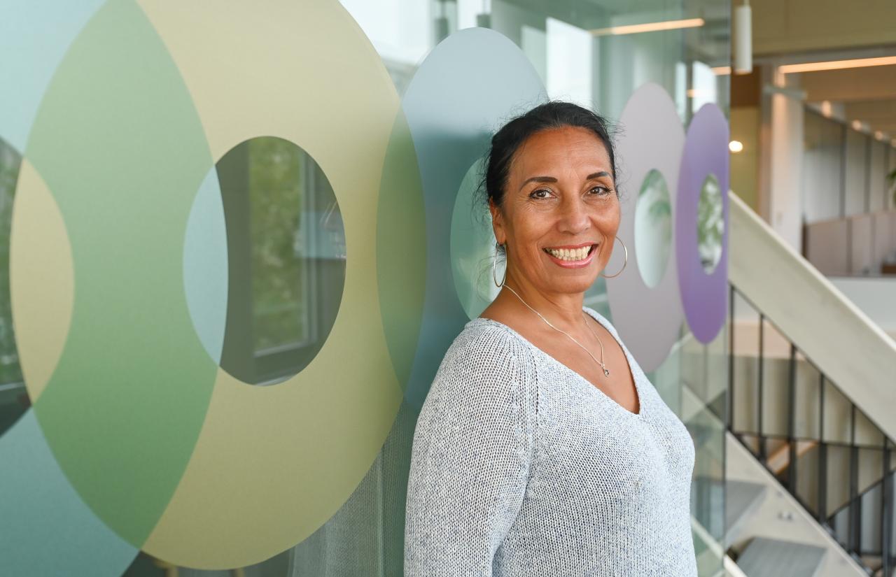 Managementondersteuner Sandra, vrouw met donker haar in staart. Ze heeft een brede glimlach en draagt een grijze trui