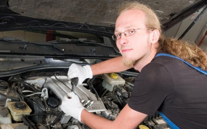 Man sleutelt aan auto