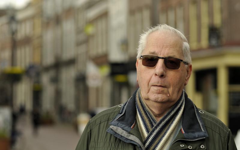 Senior man met zonnebril en sjaal om op straat