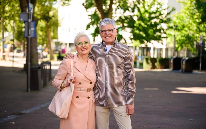 Een ouder stel staat in een winkelstraat