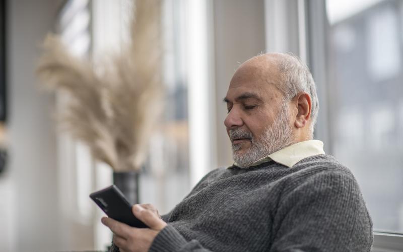 Oudere man op de bank met telefoon