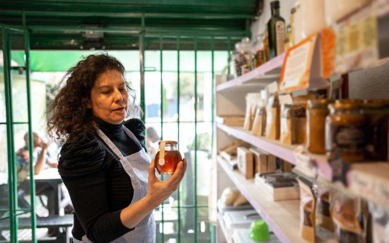 Vrouw werkzaam in een winkel heeft een pot honing vast