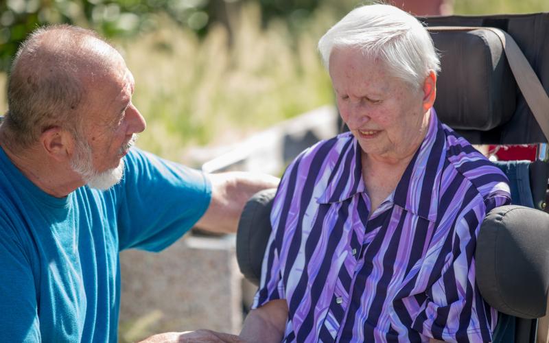 Oudere vrouw met in rolstoel met haar man naast haar