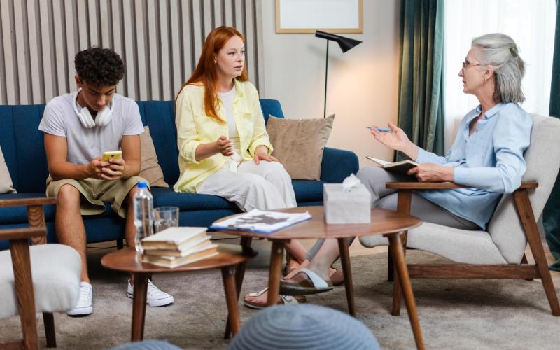 Ouder en kind praten met professional in een huiskamer setting Ouder en kind praten met professional in een huiskamer setting