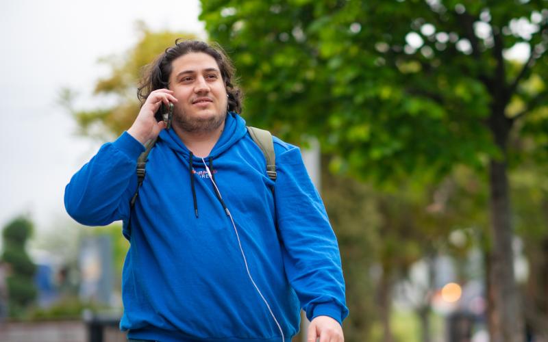 Jongvolwassen man loopt bellen op straat in een park