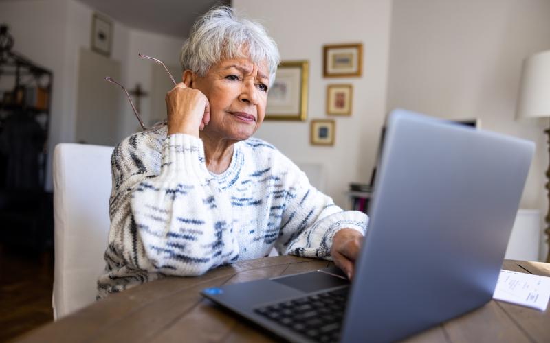 Oudere vrouw zit achter haar laptop