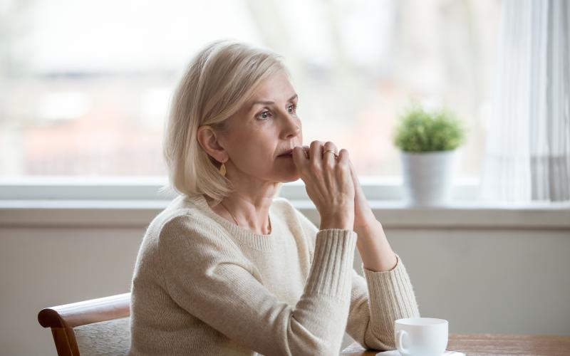 Senior vrouw kijkt bedenkelijk voor zich uit