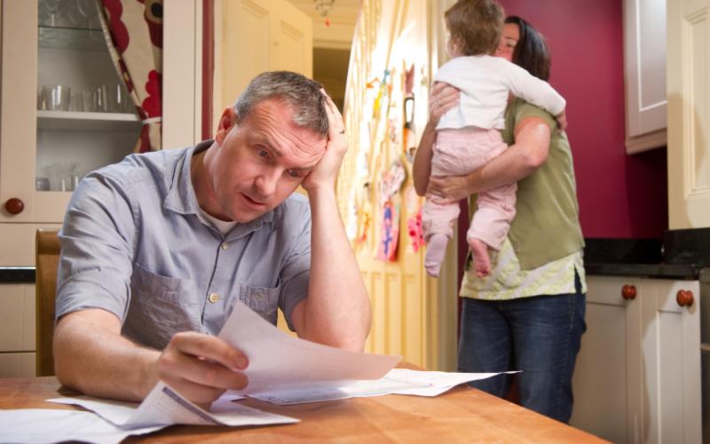 man kijkt zorgelijk naar een brief die hij leest in de keuken