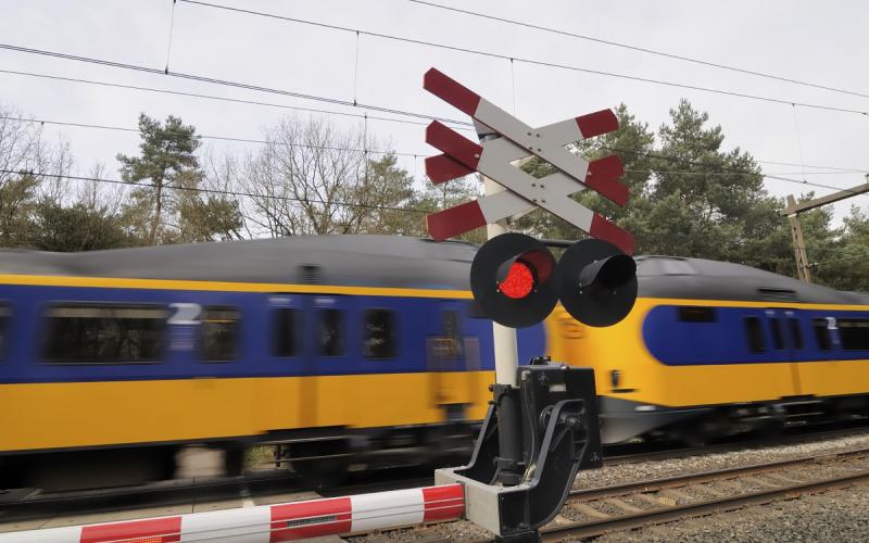 Foto van een spoorwegovergang waar een trein langs komt