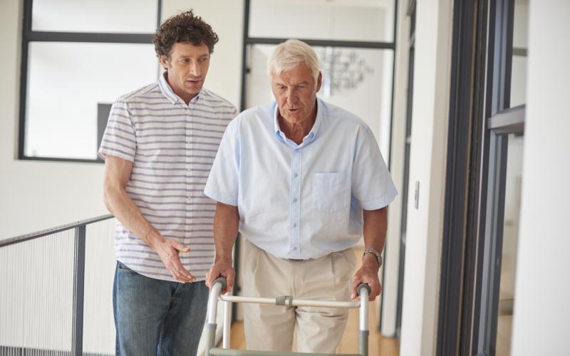 man met rollator en begeleider