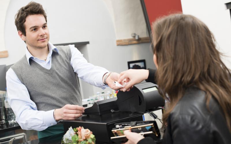 vrouw betaald contant aan de kassa, man neemt het geld in ontvangst