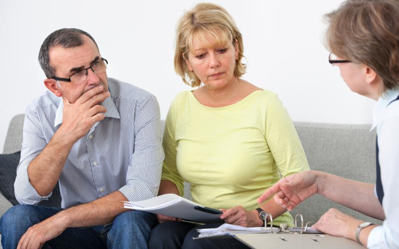 Man en vrouw, zittend op de bank, in gesprek met een man