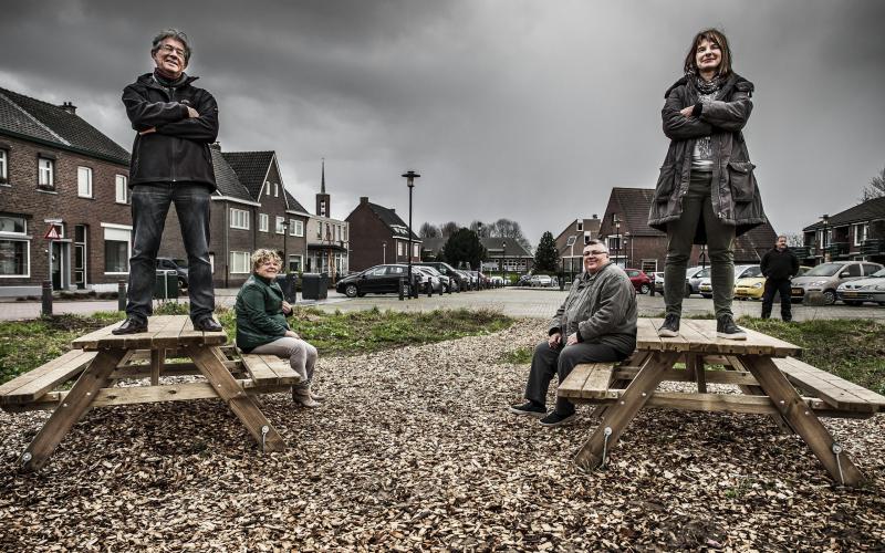 Twee mensen staan op een tafel, ernaast zitten mensen, op een woonplein