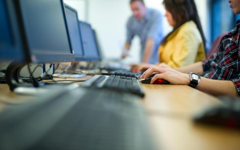 Mensen achter een computer, vrouw heeft geel shirt aan