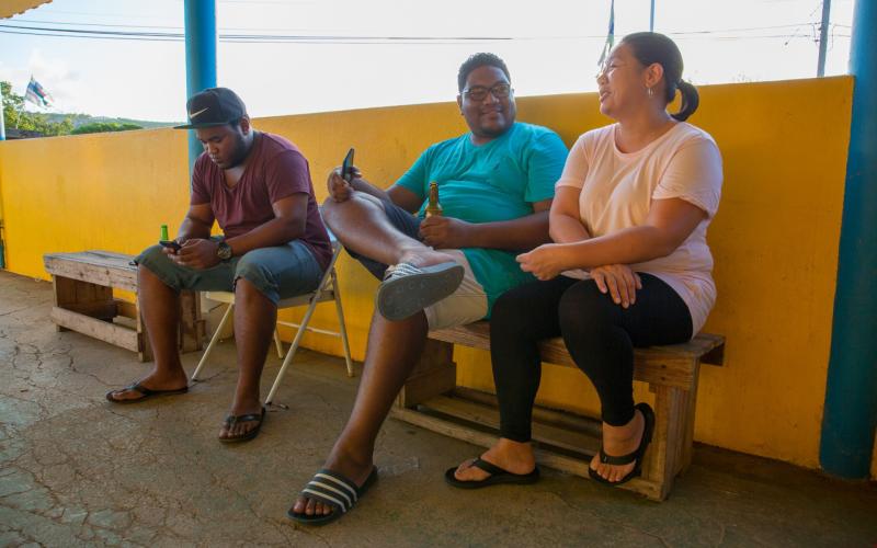 Three people sitting on a bench and talking to each other at Bonaire.