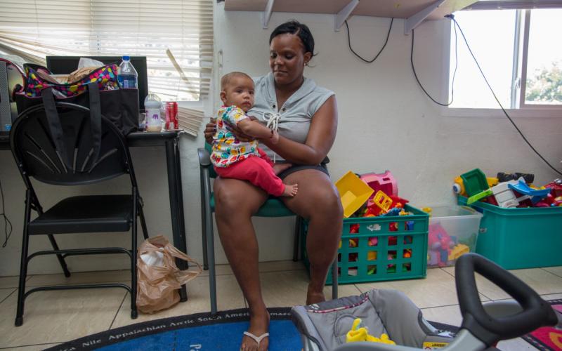 A Carribean woman holds her child on her lap