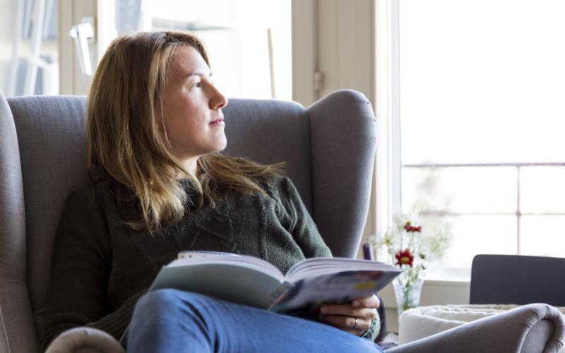 Jonge vrouw leest een boek in een stoel