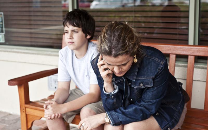 Vrouw en zoon zitten op een bankje te bellen