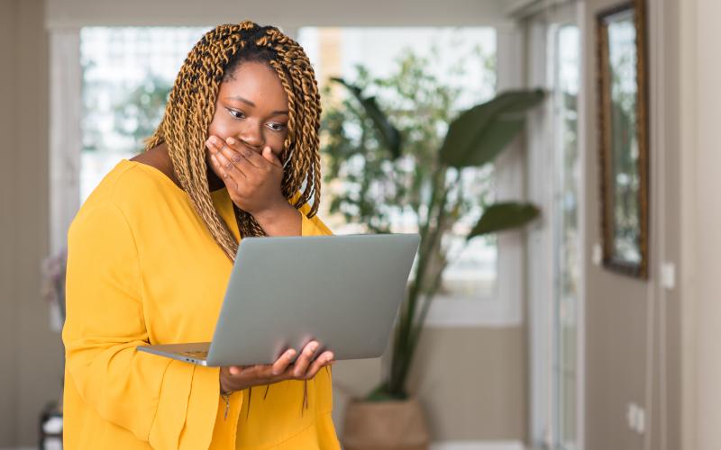 Verbaasde vrouw met laptop in haar hand