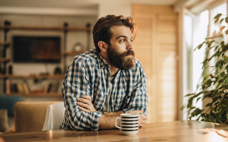 Man aan de keukentafel met koffie