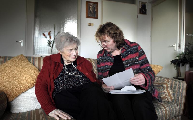 Oudere dame zittend op de bank met mevrouw van Thuiszorg