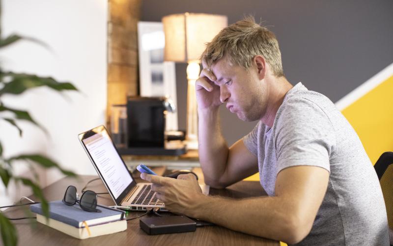 Man zit zuchtend achter zijn laptop