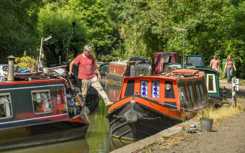 Man stapt van ene woonboot op andere woonboot