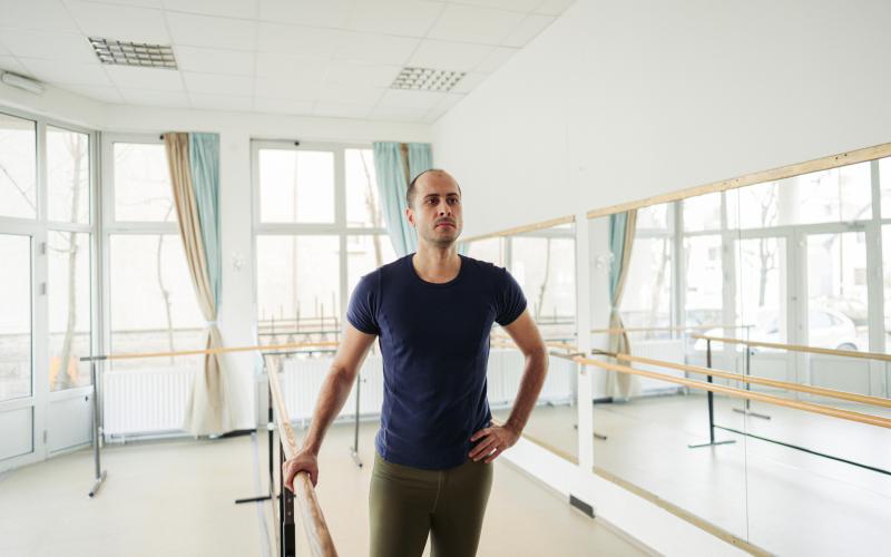 Man in dansschool met één hand op barre leuning