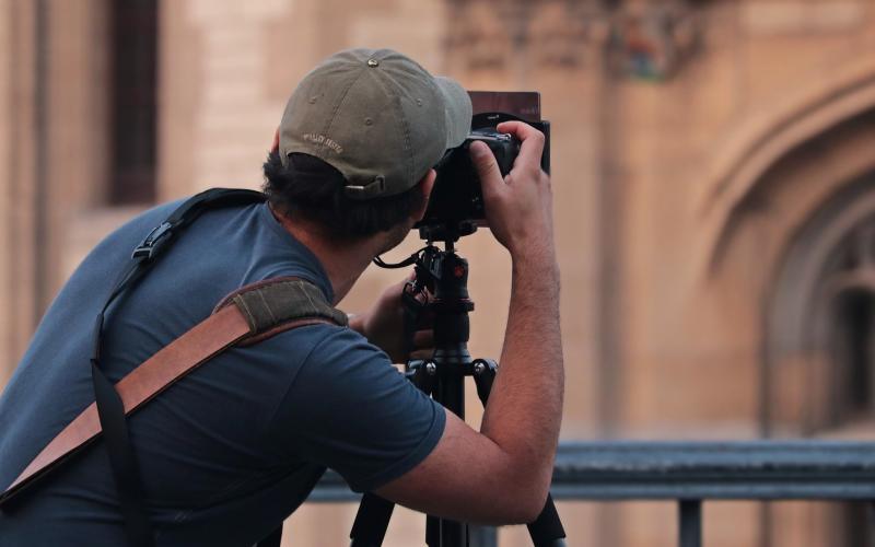 Zelfstandig ondernemer fotograaf van achter, maakt foto van gebouw