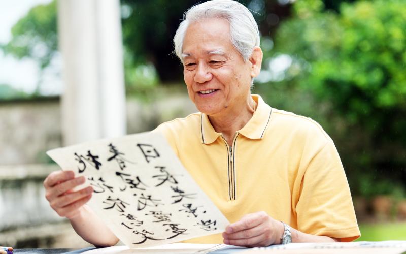 Aziatische man zit aan tafel en leest kalligrafie