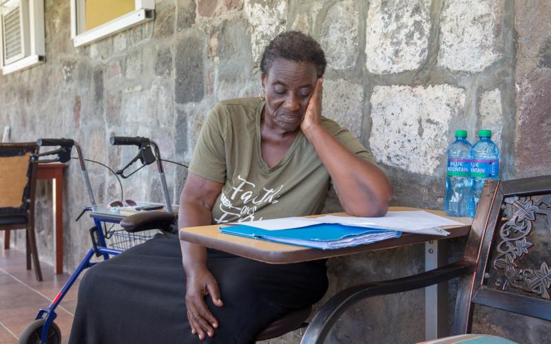 Vrouw zit aan tafel en leest document (Caribisch NL)