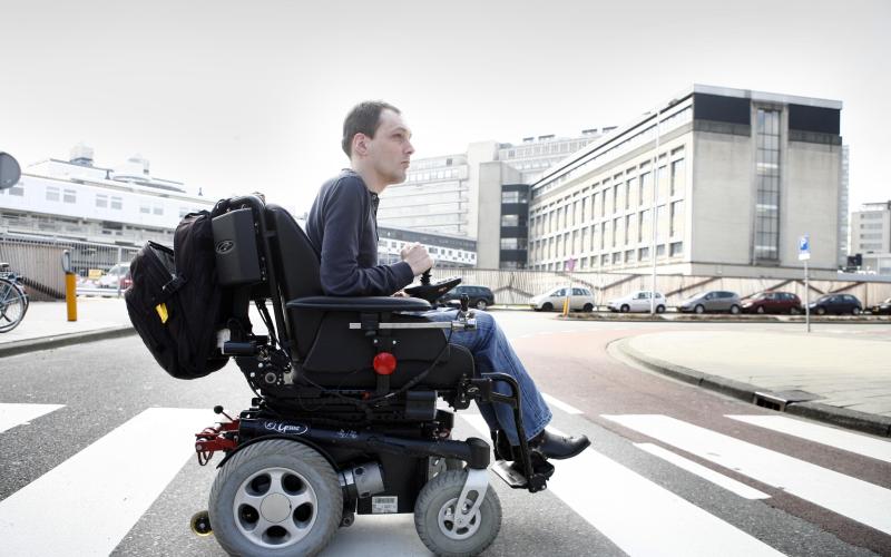 Foto van een jongen in een rolstoel op een zebrapad