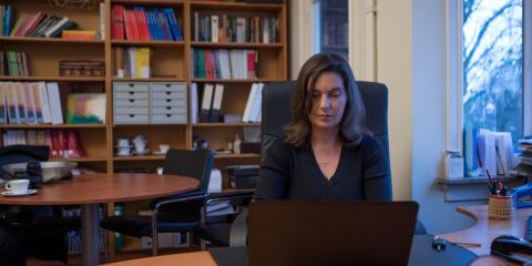 Vrouw van middelbare leeftijd zit thuis achter een bureau met een laptop