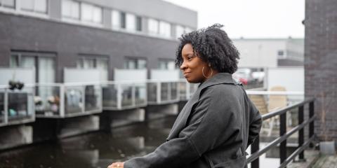 Vrouw van middelbare leeftijd staat bij haar huis aan het water