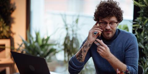 Een jonge ondernemer zit achter zijn laptop en belt met iemand