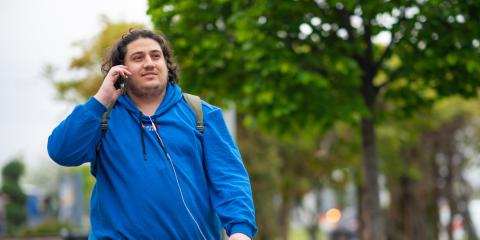 Jongvolwassen man loopt bellen op straat in een park