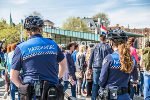 Handhavingsagenten kijken naar een groep mensen op het museumplein in Amsterdam