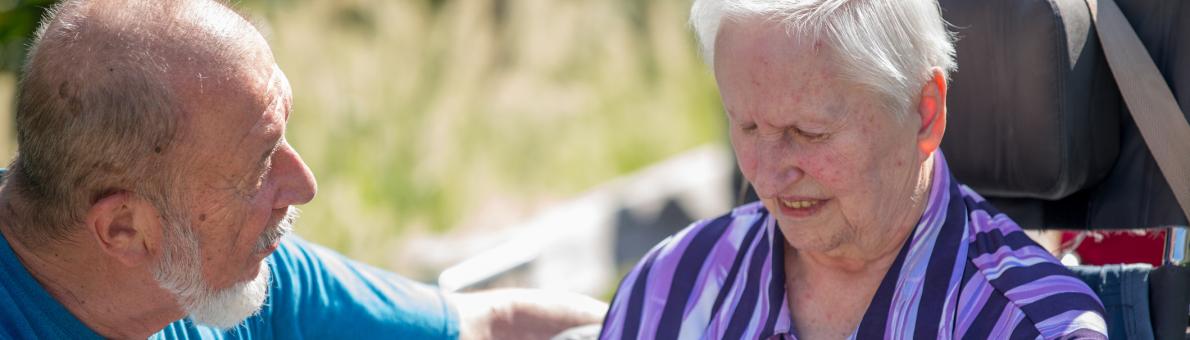 Oudere vrouw met in rolstoel met haar man naast haar