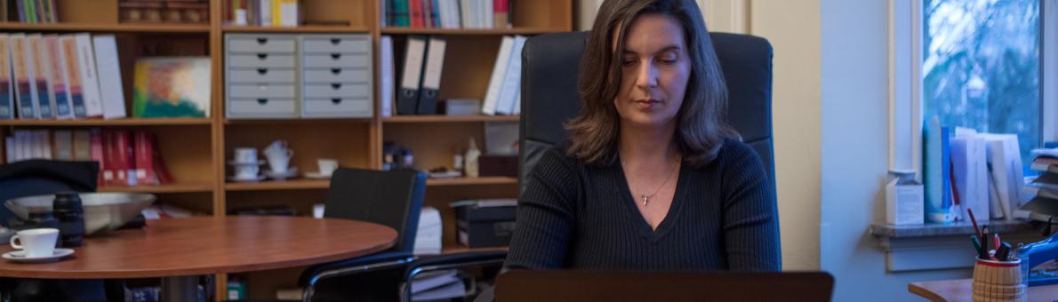 Vrouw van middelbare leeftijd zit thuis achter een bureau met een laptop