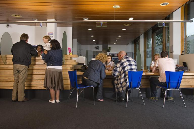 Mensen staan voor de balie van de gemeente