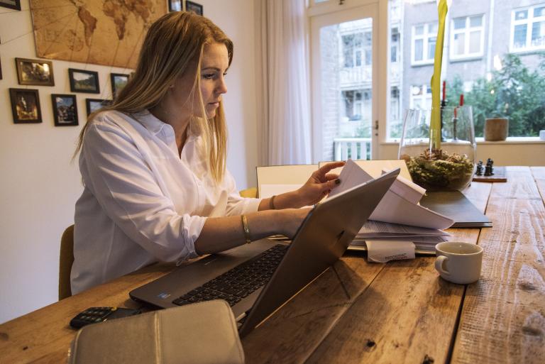 Vrouw achter laptop neemt documenten door