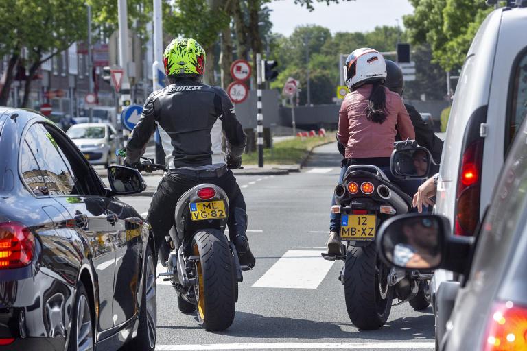 Twee motorrijders wachten voor het stoplicht