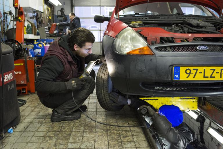 Automonteur sleutelt aan auto in garage