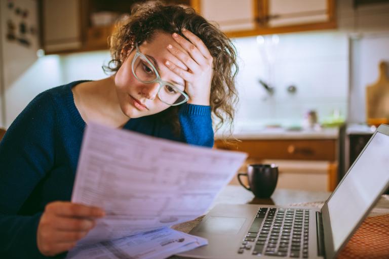 Vrouw leest formulier bij haar laptop